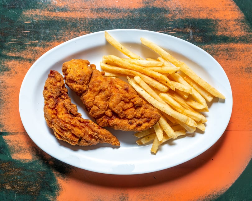 Crispy fried chicken tenders and golden french fries on a white oval plate.